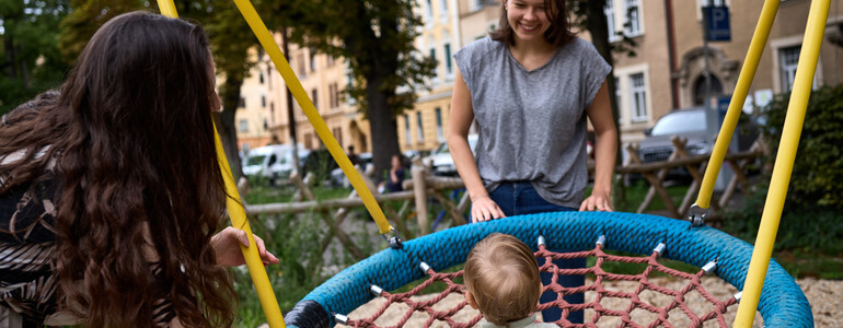 Eine Startfee spielt mit der Mutter und Kleinkind am Spielplatz