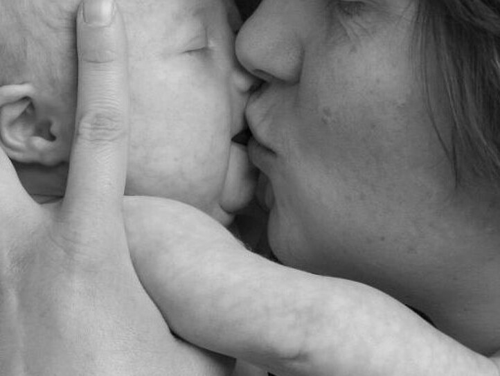 Eine Mutter hält ihr Baby und küsst es.
